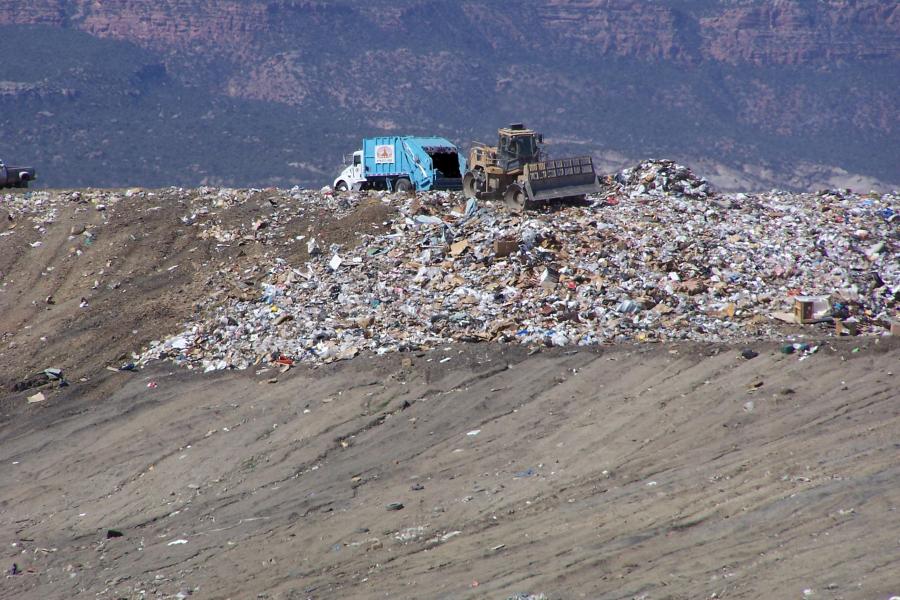 Photograph of a large pile of trash with trash truck and Front Shovel Excavator moving trash around