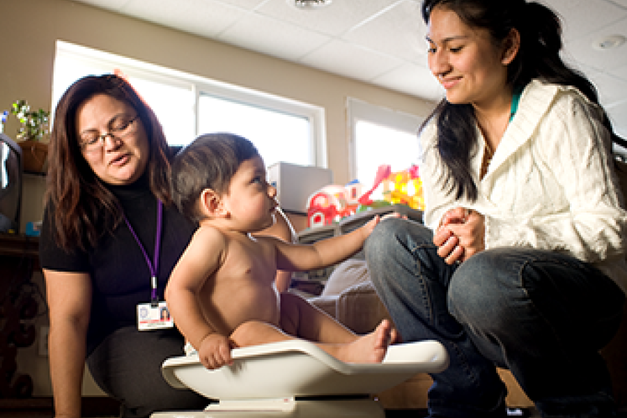 nurse visiting home and weighing toddler