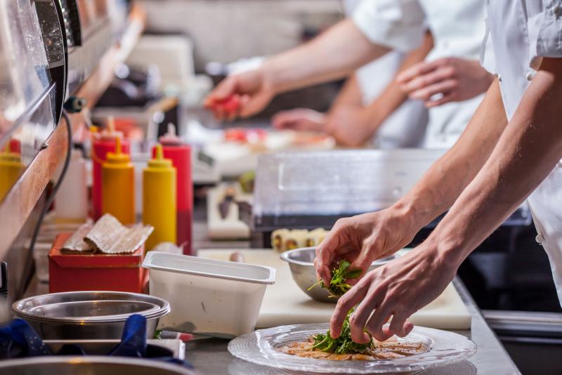 Photograph of a restaurant food preparation line with workers plating food