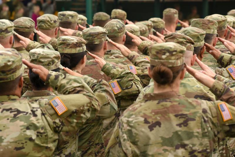 Photograph of a group of United States Soldiers dressed in fatigues, standing in lines and saluting