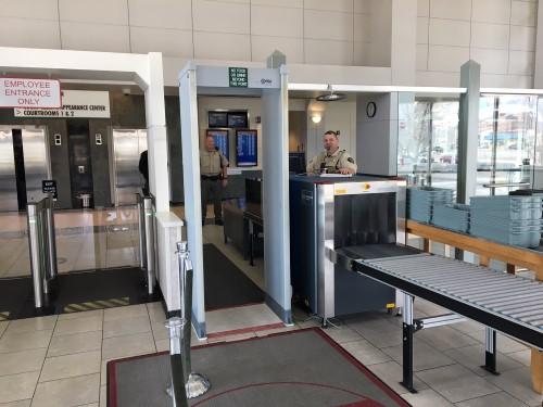 Photograph of the lobby of Mesa County Justice Center with X-ray Machine, metal detector, and deputy working at the station