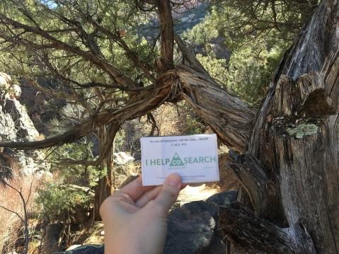 Photograph of a hiker holding a CORSAR card in their hand with trees in the background.