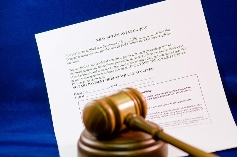 Photograph of a closeup detail of a legal notice of eviction and a wooden judge s gavel.