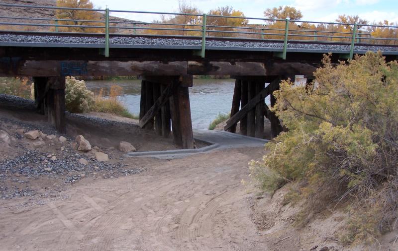 Dirt entry leading to the paved entrance of the boat ramp and the river