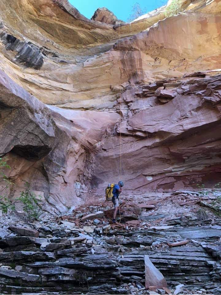 Climber taking himself off rope after rappelling from a 100ft rock ledge