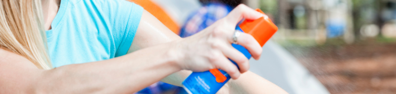 Woman spraying bug repellant on arm