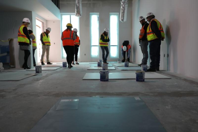 People look at paint swatches in dark room under construction. 