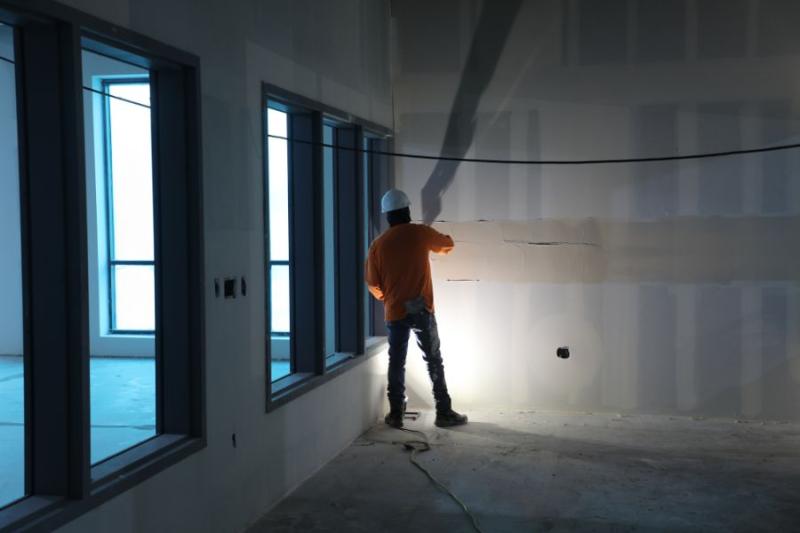 Man works on wall of Clifton Community Campus.