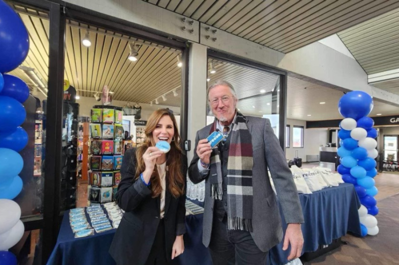 Mesa County Commissioner Bobbie Daniel and City Council Member Scot Beilfuss eat a cookie at the Breeze Airways inauguration event 