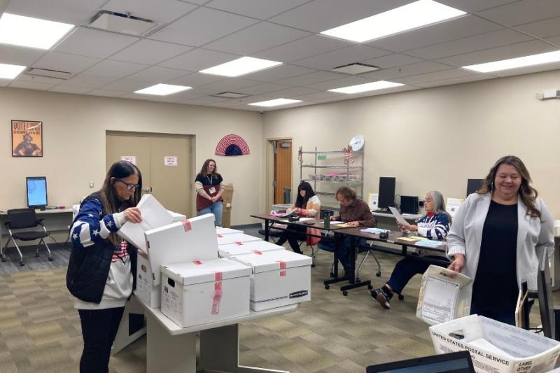 Room of people reviewing ballots. 