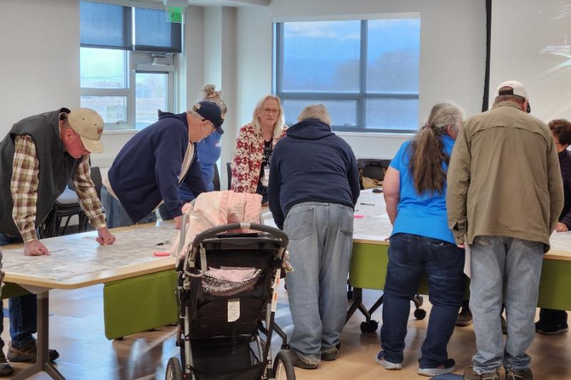 People stand around table looking at map. 