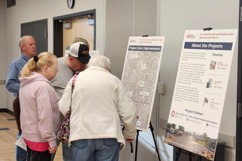 People looking at project board at open house. 