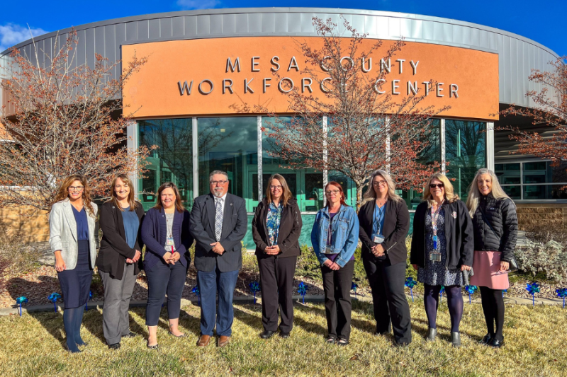 Mesa County leaders pause for a picture after planting pinwheels at the Workforce Center