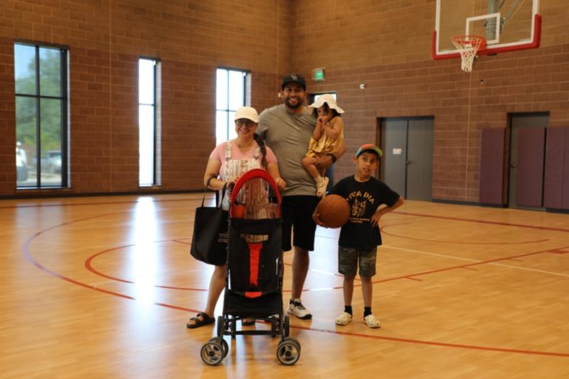 Family of four smiles for photo in gymnasium. 