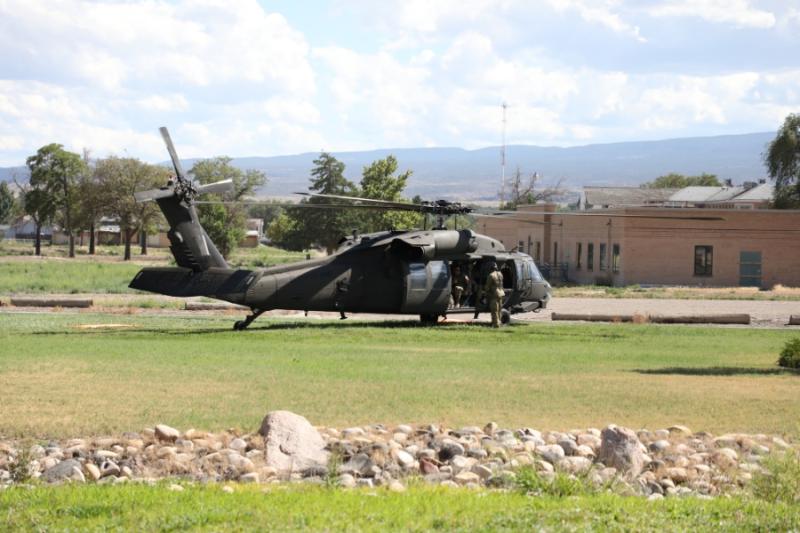 Camo military helicopter on grass. 