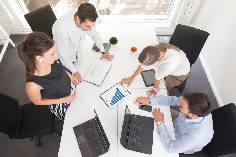 Four people sitting around a table with computers looking at a bar graph. 