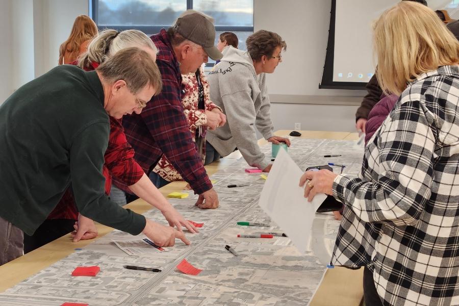 People stand around table looking at map. 