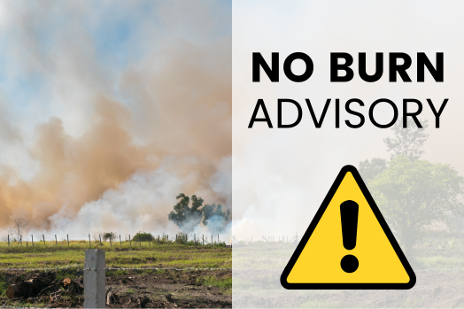 Agricultural burning in a field with a warning symbol.