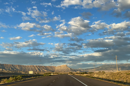 Empty highway with Mount Garfield in the background and blue skies with white clouds.