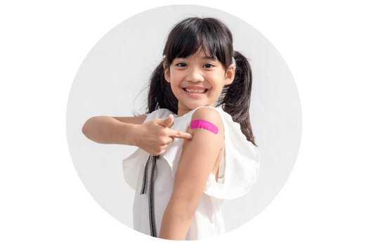 Elementary-aged girl with dark brown hair in pigtails pointing to a bright pink bandaid on her arm.