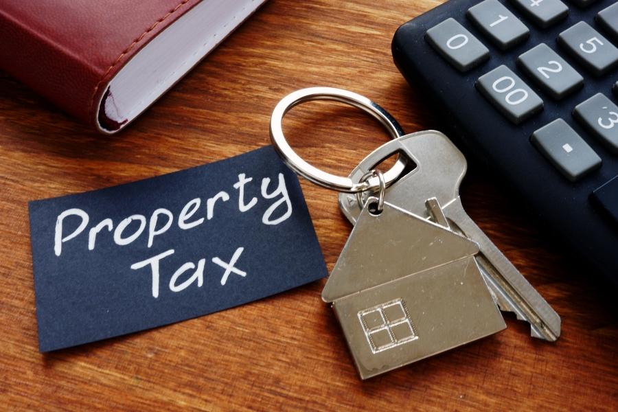 Key on house keychain next to black paper with white text reading, "property tax."