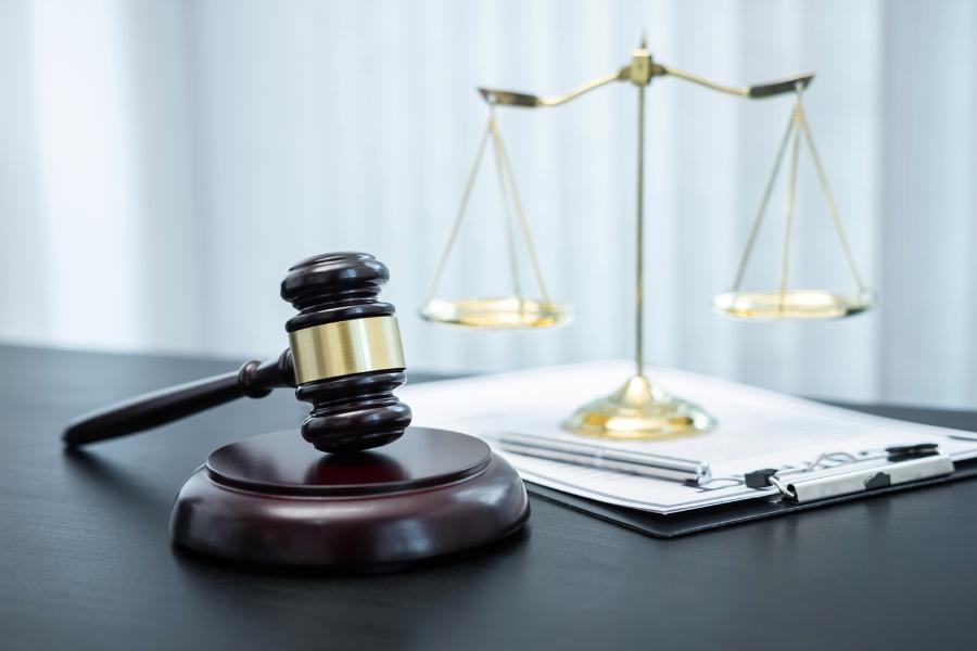 Brown and gold gavel with gold scale on a desk.