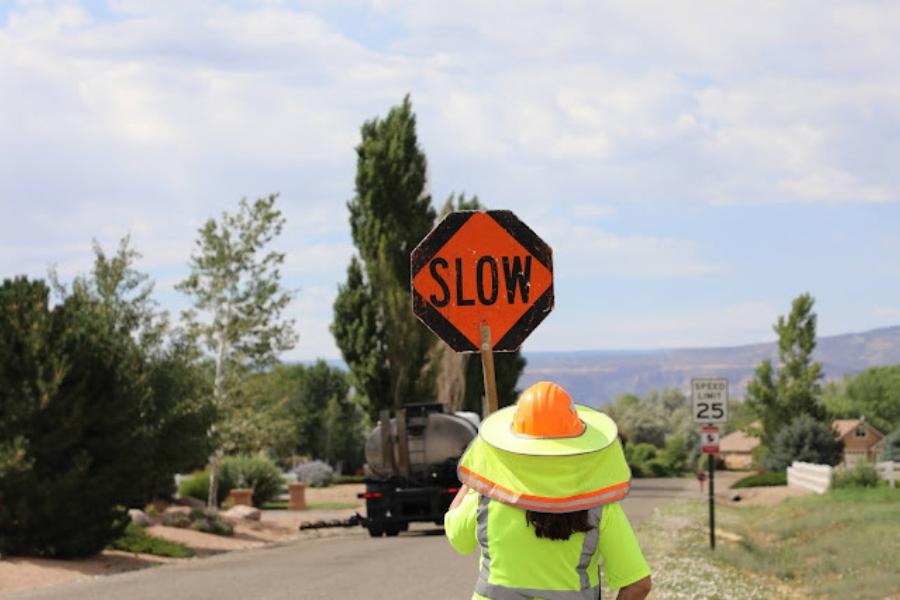 Construction worker holding orange "slow" sign. 